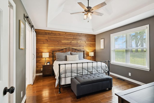 2754 Douglas Ln, Thompsons Station, TN 37179 - bedroom with baseboards, wooden walls, a tray ceiling, a barn door, and wood finished floors