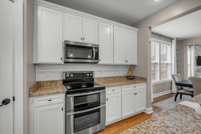 5190 Giardino Dr, Mount Juliet, TN 37122 - kitchen featuring appliances with stainless steel finishes, light wood-type flooring, backsplash, white cabinetry, and light stone countertops