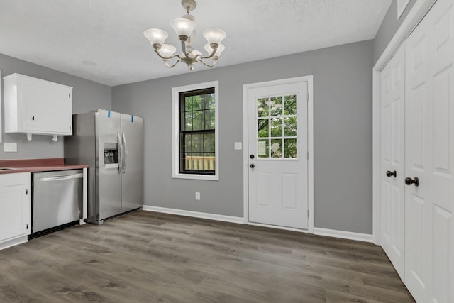 3728 Wharton Dr, Nashville, TN 37211 - kitchen featuring appliances with stainless steel finishes, white cabinets, a chandelier, dark wood finished floors, and baseboards