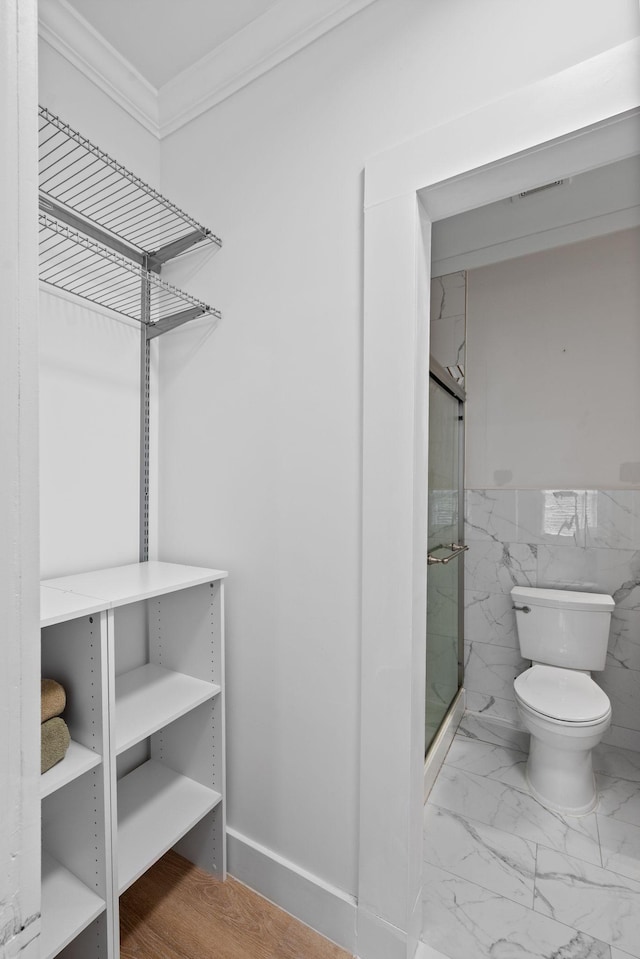 116 31st Ave N Unit 104, Nashville, TN 37203 - bathroom featuring ornamental molding, a shower stall, marble finish floors, and tile walls
