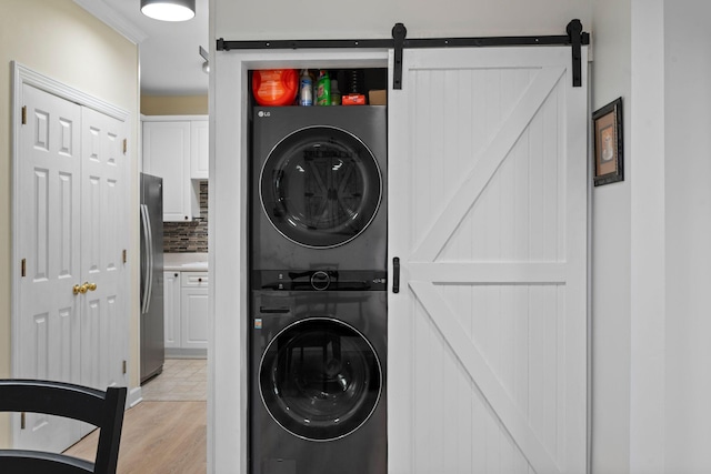 116 31st Ave N Unit 104, Nashville, TN 37203 - washroom featuring stacked washer / drying machine, a barn door, and light wood-type flooring