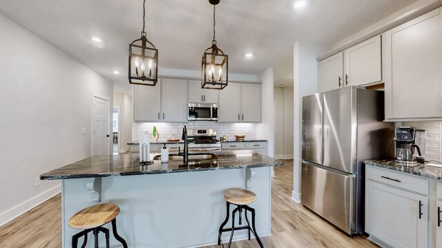 1137 Fiona Dr, Lebanon, TN 37087 - kitchen with stainless steel appliances, a breakfast bar area, baseboards, light wood-style floors, and recessed lighting