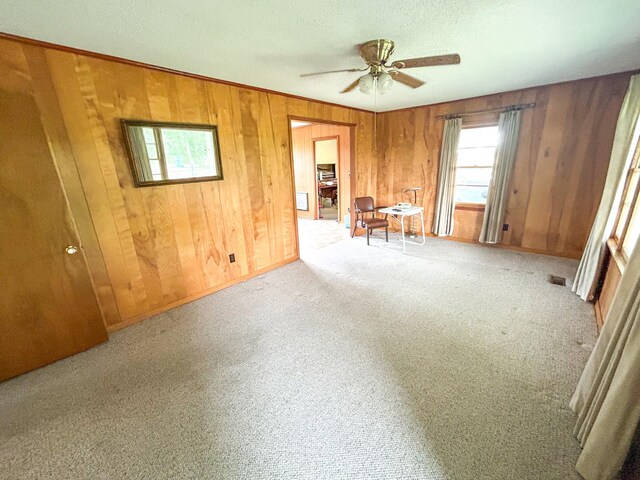 72 Allen Ln, Huntingdon, TN 38344 - unfurnished room with healthy amount of natural light, a ceiling fan, wood walls, carpet flooring, and a textured ceiling