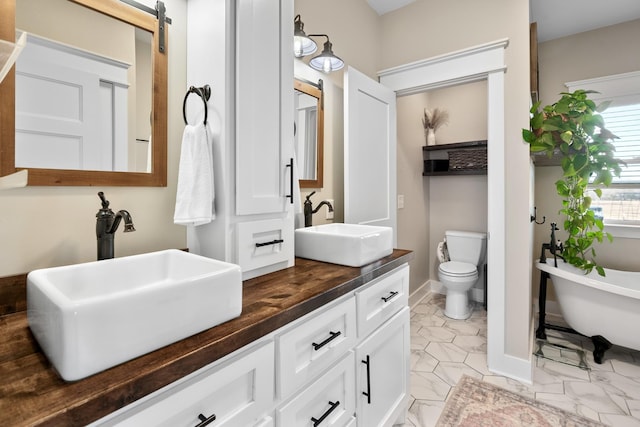 2824 Robert Truelove Rd, Columbia, TN 38401 - bathroom featuring double vanity, a freestanding tub, baseboards, and toilet