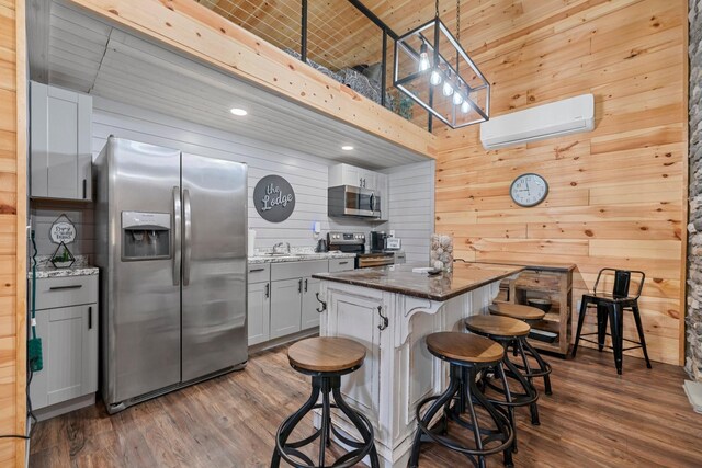 266 Campground Rd, Olmstead, KY 42265 - kitchen featuring appliances with stainless steel finishes, a wall unit AC, wood walls, dark wood finished floors, and a breakfast bar area