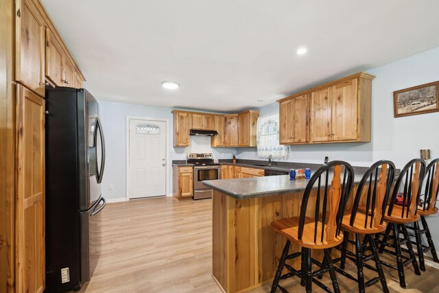 1540 Centerville Hwy, Hohenwald, TN 38462 - kitchen featuring appliances with stainless steel finishes, a peninsula, under cabinet range hood, dark countertops, and a kitchen breakfast bar