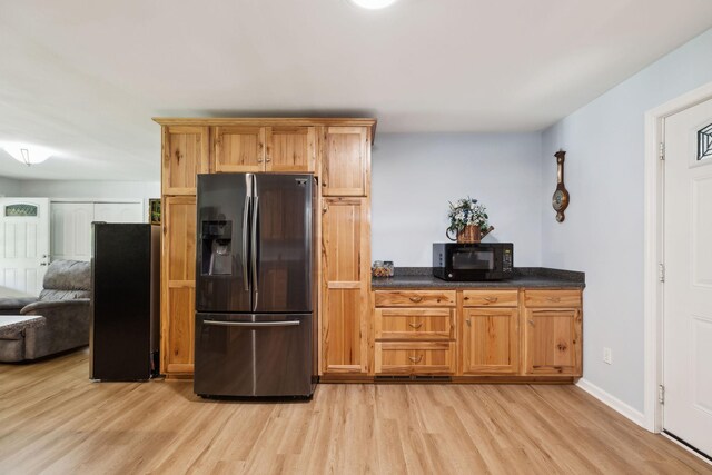 1540 Centerville Hwy, Hohenwald, TN 38462 - kitchen with stainless steel refrigerator with ice dispenser, black microwave, light wood finished floors, dark countertops, and baseboards