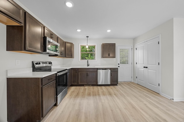 174 Oak St, Clarksville, TN 37042 - kitchen featuring appliances with stainless steel finishes, light wood-style floors, dark brown cabinets, recessed lighting, and light countertops