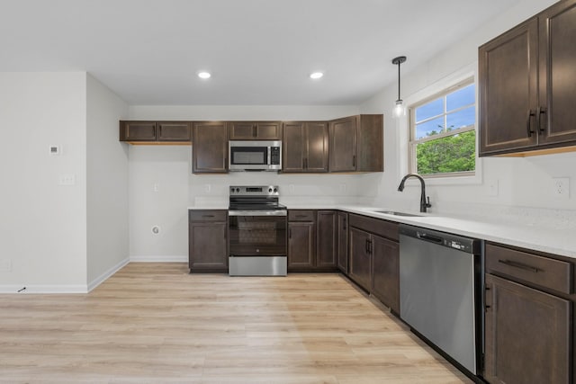 174 Oak St, Clarksville, TN 37042 - kitchen featuring stainless steel appliances, a sink, light wood-style floors, dark brown cabinetry, and recessed lighting
