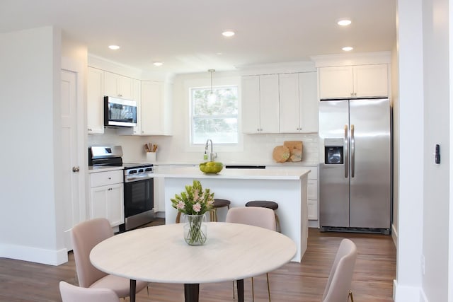 2513 Hickory Dr, Springfield, TN 37172 - kitchen featuring appliances with stainless steel finishes, dark wood-type flooring, light countertops, white cabinets, and tasteful backsplash