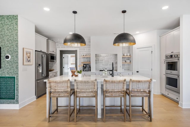 4042 Flowing Creek Dr, Franklin, TN 37064 - kitchen featuring stainless steel appliances, open shelves, light countertops, a breakfast bar, and light wood-type flooring
