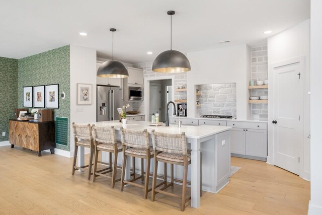 4042 Flowing Creek Dr, Franklin, TN 37064 - kitchen with stainless steel appliances, light wood-style flooring, light countertops, tasteful backsplash, and a breakfast bar area