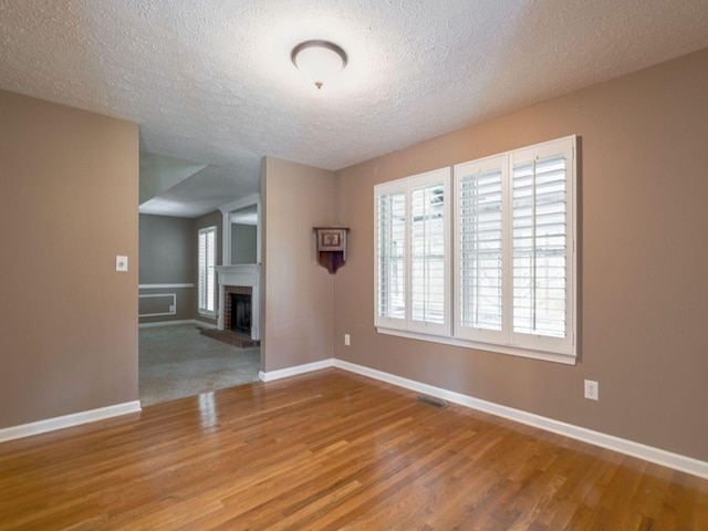 2999 Cages Bend Rd, Gallatin, TN 37066 - unfurnished living room featuring wood finished floors, a brick fireplace, baseboards, and a textured ceiling