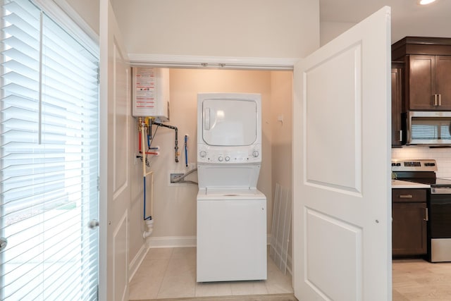 3254 Tasker Dr, Antioch, TN 37013 - laundry area with stacked washing machine and dryer, tankless water heater, baseboards, and light tile patterned floors