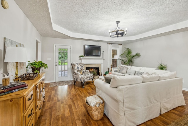 124 Mabry Dr, Murfreesboro, TN 37127 - living room featuring a chandelier, a textured ceiling, wood finished floors, a warm lit fireplace, and a raised ceiling