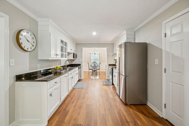124 Mabry Dr, Murfreesboro, TN 37127 - kitchen with appliances with stainless steel finishes, light wood-style flooring, white cabinetry, dark countertops, and ornamental molding