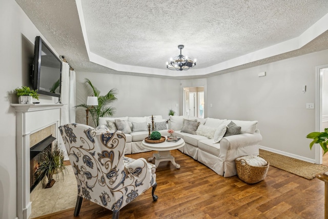 124 Mabry Dr, Murfreesboro, TN 37127 - living area with a textured ceiling, a tray ceiling, a chandelier, wood finished floors, and a tiled fireplace