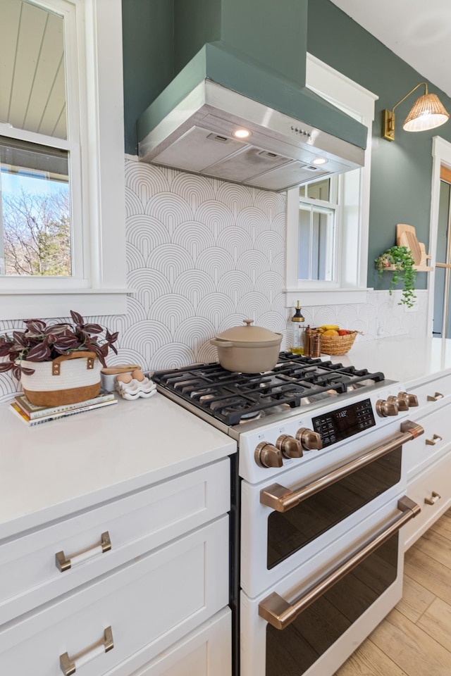 1222 Rock Church Rd, Dickson, TN 37055 - kitchen with range with two ovens, wall chimney exhaust hood, decorative backsplash, white cabinets, and light countertops
