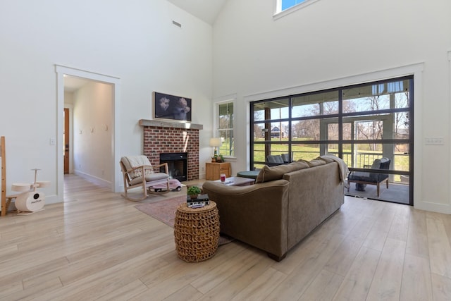 1222 Rock Church Rd, Dickson, TN 37055 - living room featuring light wood finished floors, high vaulted ceiling, healthy amount of natural light, a fireplace, and baseboards