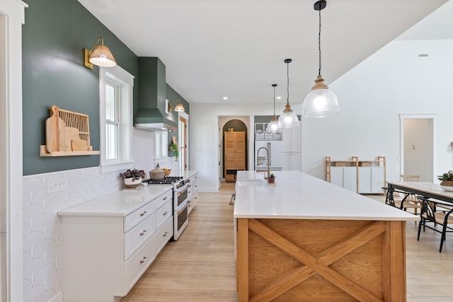 1222 Rock Church Rd, Dickson, TN 37055 - kitchen featuring wall chimney range hood, premium appliances, light wood-type flooring, light countertops, and hanging light fixtures
