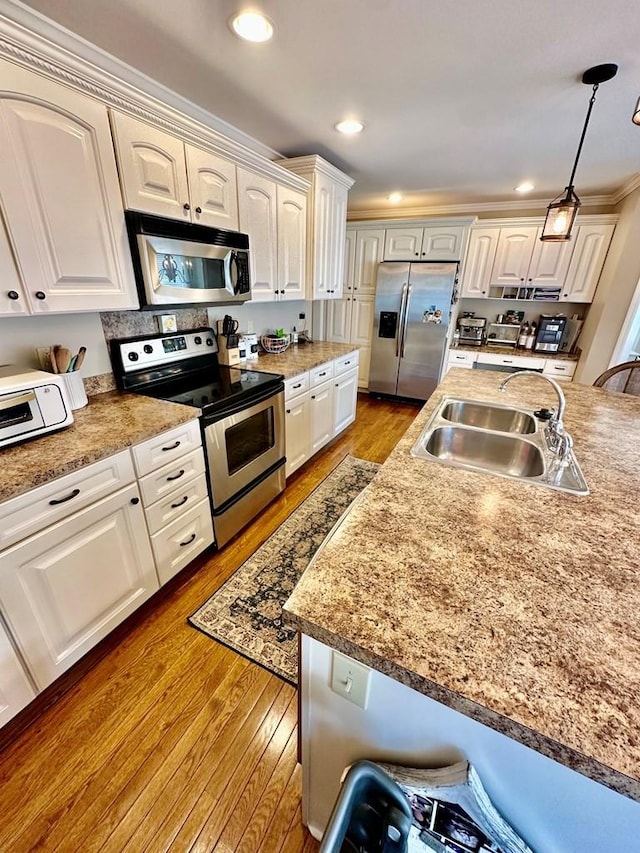593 Imperial Dr, Sparta, TN 38583 - kitchen featuring appliances with stainless steel finishes, a sink, hardwood / wood-style flooring, pendant lighting, and white cabinets