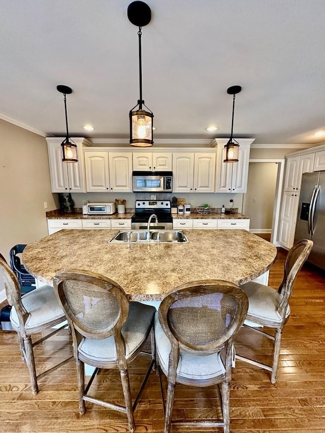 593 Imperial Dr, Sparta, TN 38583 - kitchen featuring appliances with stainless steel finishes, wood finished floors, a sink, a kitchen breakfast bar, and crown molding