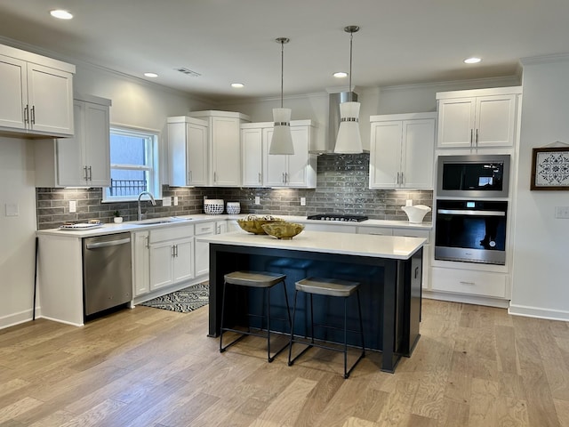 6705 Major Hutchings Dr, Hermitage, TN 37076 - kitchen featuring appliances with stainless steel finishes, wall chimney range hood, a sink, a kitchen island, and light countertops