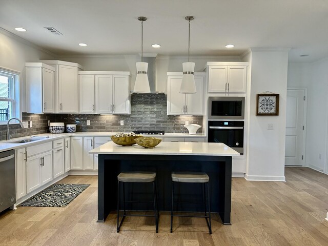 6705 Major Hutchings Dr, Hermitage, TN 37076 - kitchen with stainless steel appliances, a sink, wall chimney exhaust hood, a center island, and light countertops