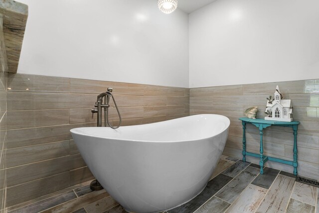 1313 Stayton Rd, Cumberland Furnace, TN 37051 - bathroom featuring a freestanding tub, tile walls, wainscoting, and wood finished floors
