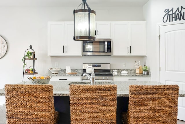 4043 Beach Way, White House, TN 37188 - kitchen with appliances with stainless steel finishes, an island with sink, white cabinetry, and light stone countertops