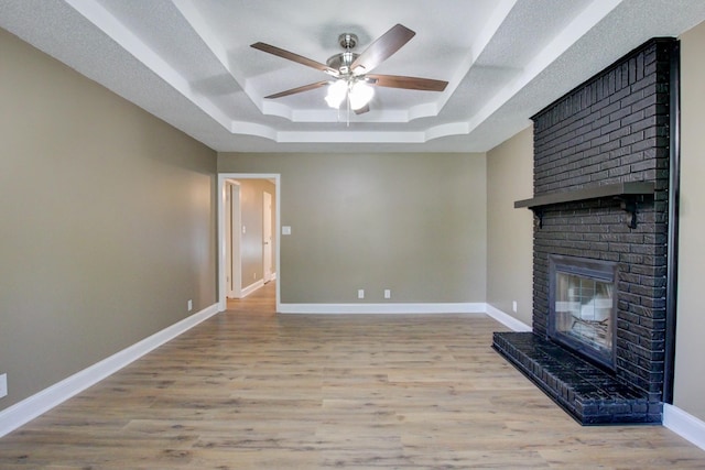 1783 Forrestdale Dr, Clarksville, TN 37042 - unfurnished living room with a raised ceiling, ceiling fan, a brick fireplace, baseboards, and wood finished floors