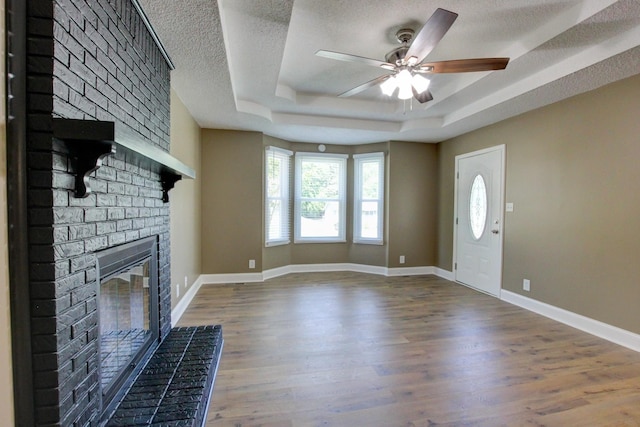 1783 Forrestdale Dr, Clarksville, TN 37042 - unfurnished living room with a raised ceiling, a brick fireplace, ceiling fan, a textured ceiling, and wood finished floors