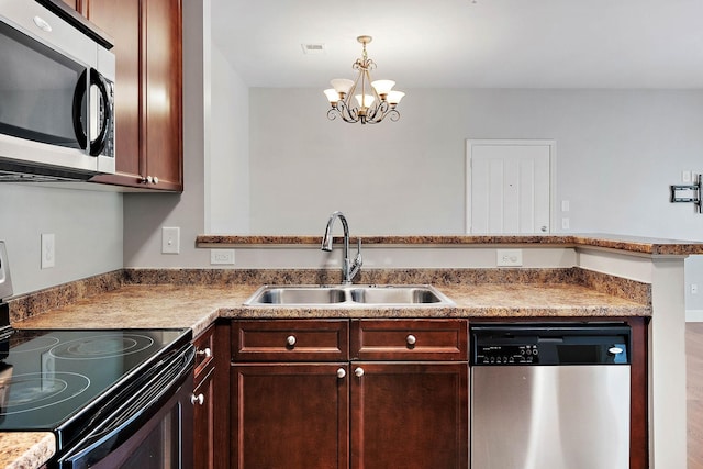 8221 Lenox Creekside Dr Unit 10, Antioch, TN 37013 - kitchen featuring stainless steel appliances, a sink, a chandelier, hanging light fixtures, and a peninsula