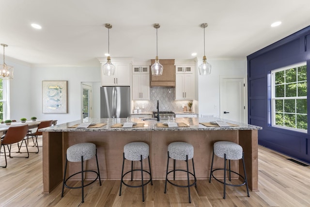 712 N 5th St, Nashville, TN 37207 - kitchen with freestanding refrigerator, backsplash, white cabinets, a large island with sink, and light wood finished floors