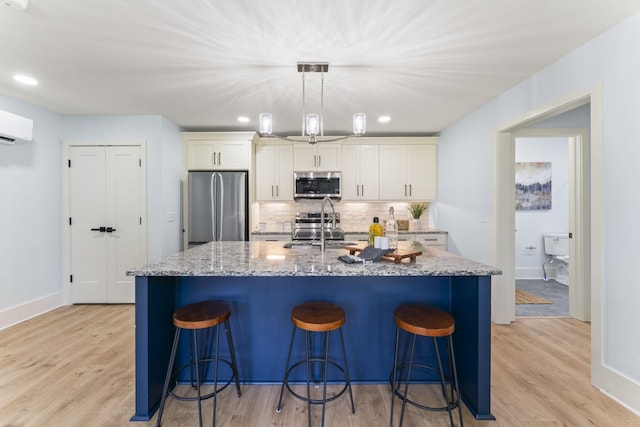 712 N 5th St, Nashville, TN 37207 - kitchen featuring stainless steel appliances, light wood-style flooring, decorative backsplash, a kitchen island with sink, and recessed lighting