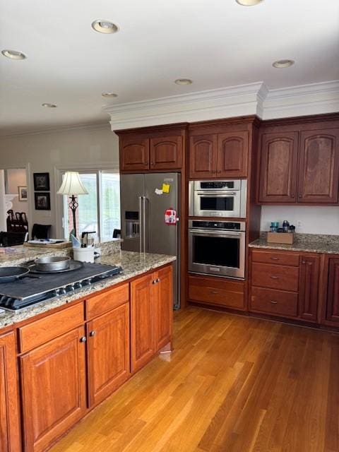 106 Rigney Rd, Manchester, TN 37355 - kitchen with appliances with stainless steel finishes, light stone counters, light wood-style flooring, and ornamental molding