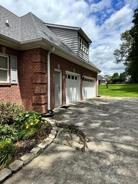 106 Rigney Rd, Manchester, TN 37355 - view of home's exterior with concrete driveway, brick siding, a garage, roof with shingles, and a lawn