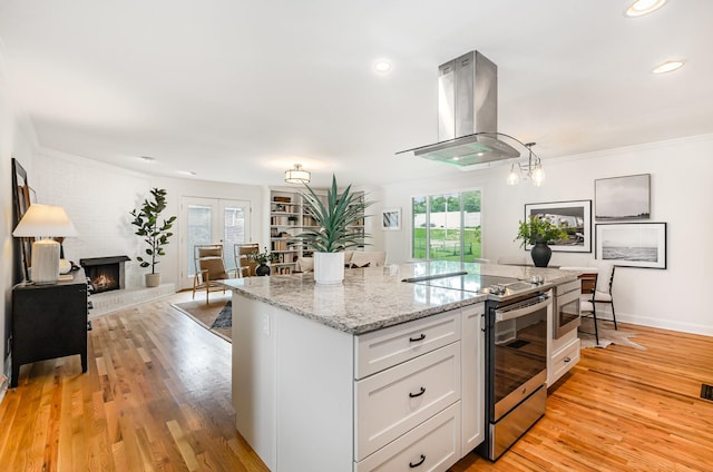 109 Pebble Creek Rd, Franklin, TN 37064 - kitchen with stainless steel range with electric stovetop, island exhaust hood, white cabinetry, light wood-style flooring, and crown molding
