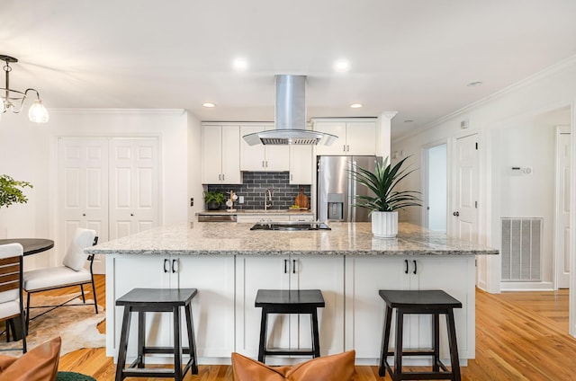 109 Pebble Creek Rd, Franklin, TN 37064 - kitchen featuring appliances with stainless steel finishes, island exhaust hood, crown molding, white cabinets, and a kitchen breakfast bar