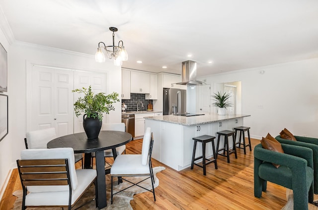 109 Pebble Creek Rd, Franklin, TN 37064 - kitchen featuring island exhaust hood, stainless steel appliances, ornamental molding, white cabinets, and a kitchen bar