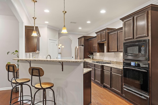 2034 Lincoln Rd, Spring Hill, TN 37174 - kitchen with black appliances, a breakfast bar area, dark brown cabinets, light wood-type flooring, and a warming drawer