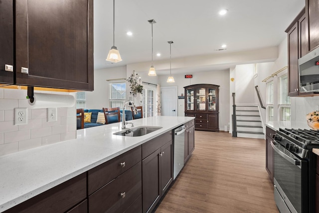 8061 Warbler Way, Brentwood, TN 37027 - kitchen with a sink, appliances with stainless steel finishes, dark brown cabinets, decorative backsplash, and light wood finished floors