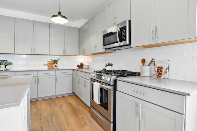 836 Ewell Farm Dr, Spring Hill, TN 37174 - kitchen featuring stainless steel appliances, light wood-style floors, tasteful backsplash, light countertops, and pendant lighting