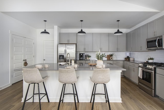836 Ewell Farm Dr, Spring Hill, TN 37174 - kitchen with appliances with stainless steel finishes, gray cabinetry, tasteful backsplash, a kitchen breakfast bar, and wood finished floors