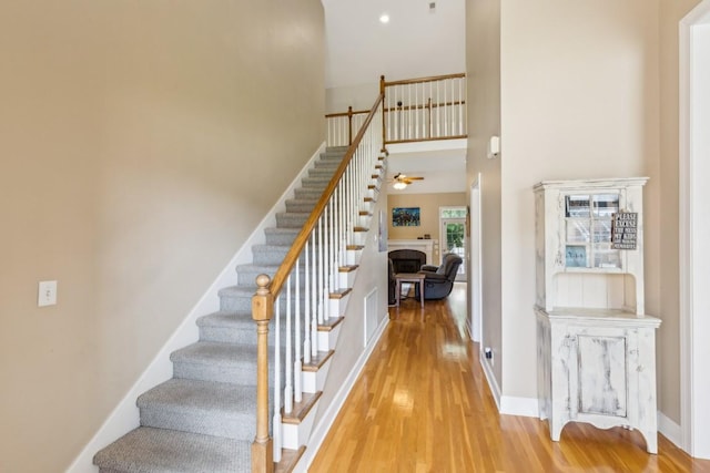 2931 Runnymeade Dr, Murfreesboro, TN 37127 - stairs featuring wood finished floors, a fireplace, a ceiling fan, baseboards, and a towering ceiling