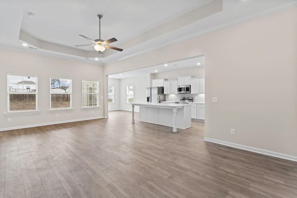 1129 Bluecreek Cir, Murfreesboro, TN 37129 - unfurnished living room featuring a raised ceiling, a ceiling fan, recessed lighting, plenty of natural light, and wood finished floors