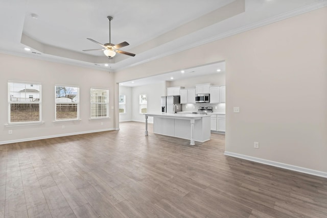1129 Bluecreek Cir, Murfreesboro, TN 37129 - unfurnished living room featuring a raised ceiling, a ceiling fan, recessed lighting, plenty of natural light, and wood finished floors