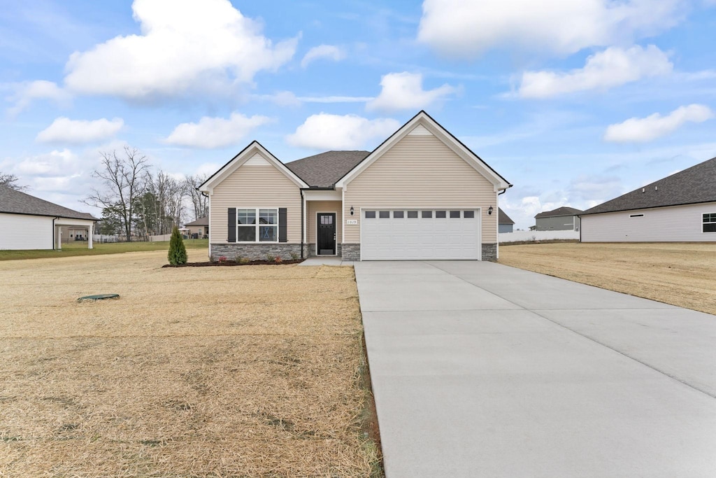 1129 Bluecreek Cir, Murfreesboro, TN 37129 - view of front facade featuring concrete driveway, stone siding, an attached garage, and a front yard
