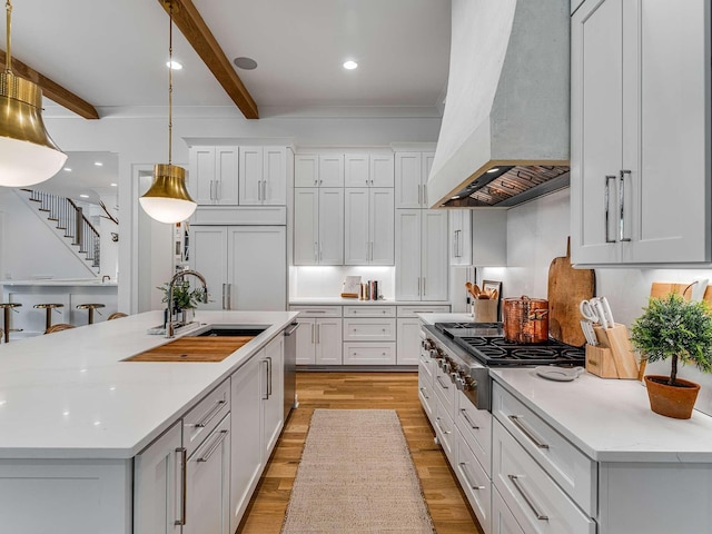 9021 Passiflora Ct, College Grove, TN 37046 - kitchen featuring premium range hood, stainless steel appliances, beamed ceiling, a sink, and light wood finished floors
