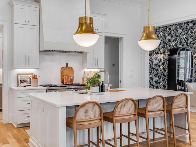 9021 Passiflora Ct, College Grove, TN 37046 - kitchen featuring light wood-type flooring, premium range hood, a center island with sink, light countertops, and white cabinetry